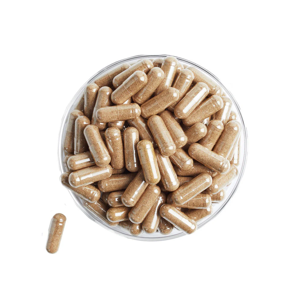 Glass bowl filled with brown capsules on a white background