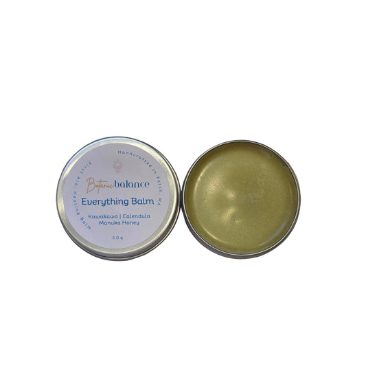 Open tin of balm with lid on a speckled countertop