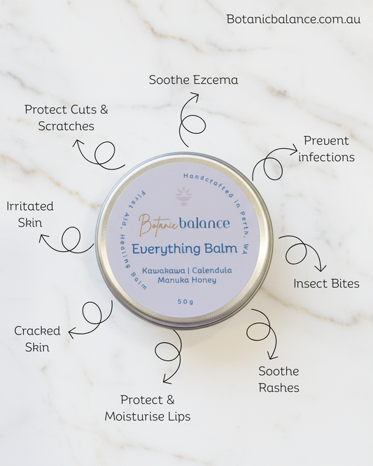 Everything Balm tin with usage benefits on a marble background